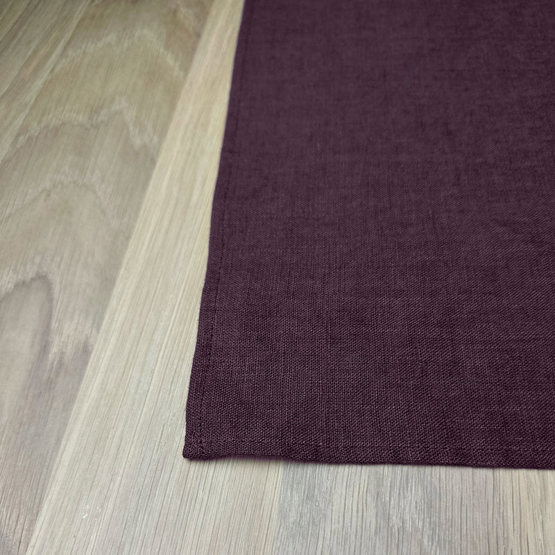 Corner-of-Aubergine-linen-placemat-on-wooden-table