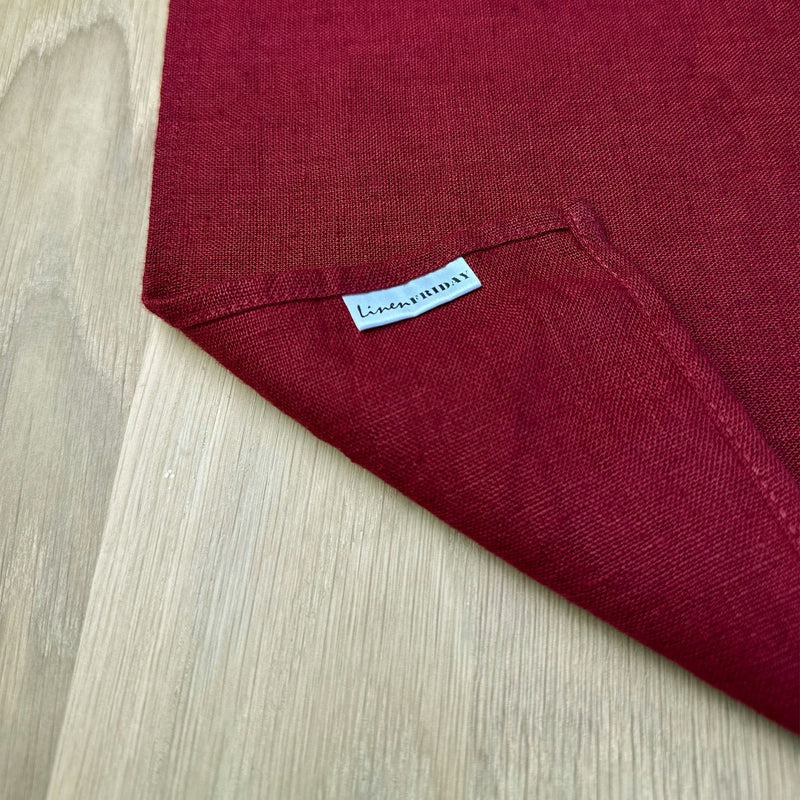 Corner-of-carmine-red-linen-placemat-with-label-of-LinenFriday-on-wooden-table